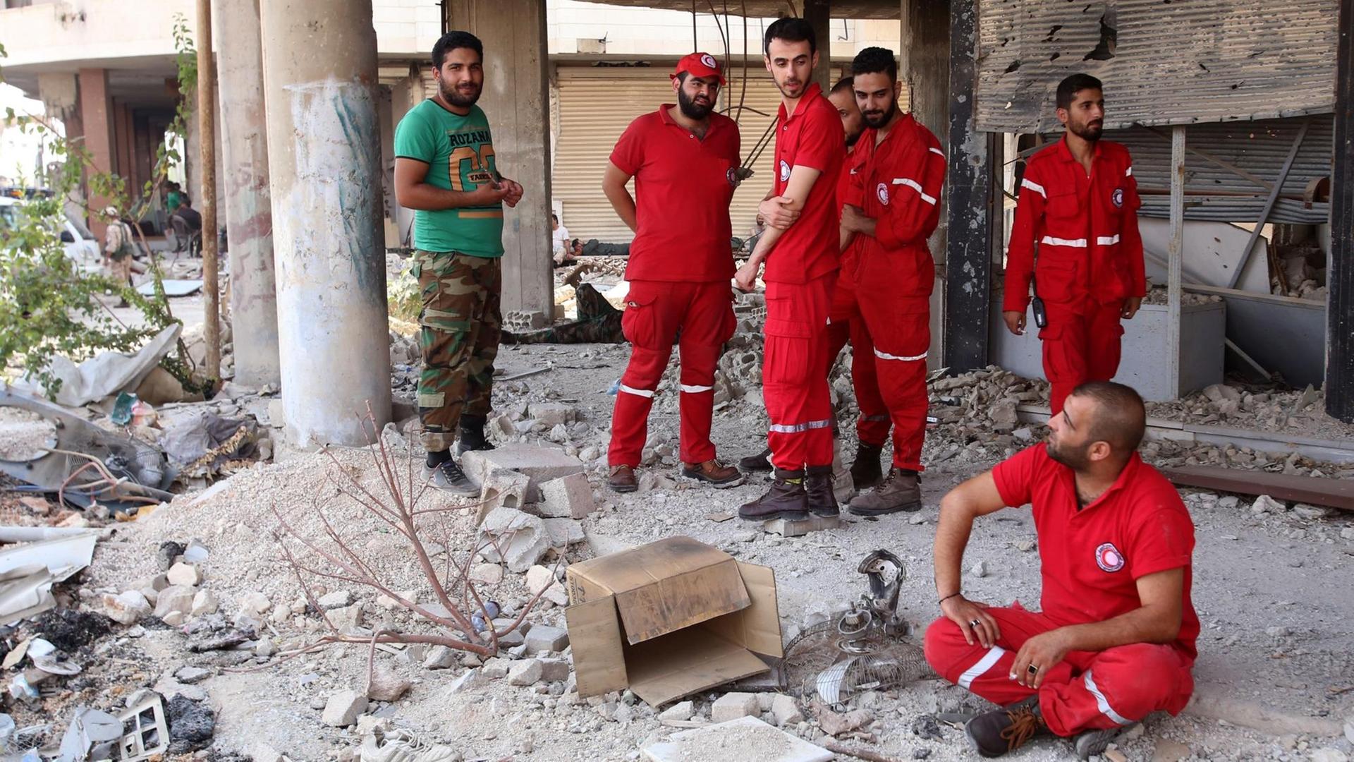 Mitarbeiter des Roten Kreuzes und ein syrischer Soldat warten auf die Räumung von Daraja. Mitarbeiter des Roten Kreuzes und ein syrischer Soldat warten auf die Räumung von Daraja.