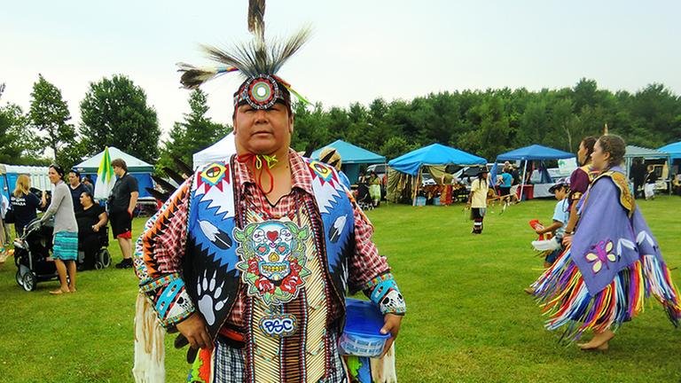 Ein Gast auf dem Pow Wow in Ontario, im Hintergrund tanzende Mädchen. Ein Gast auf dem Pow Wow in Ontario, im Hintergrund tanzende Mädchen.