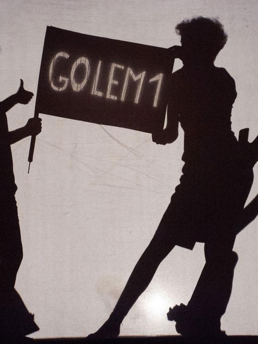 Die deutsche Schauspielerin Juliette Schenkel (l) und die italienische Schauspielerin Silvia Sassetti stehen am 18.07.2015 während der Fotoprobe für das Stummtheater "Golem" in Weimar (Thüringen) hinter einer Leinwand auf der Bühne.