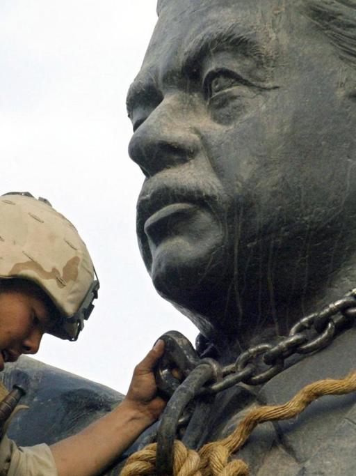 Ein US-Soldat legte 2003 eine Kette um den Kopf der Statue von Saddam Hussein, was den Sturz des irakischen Diktators verbildlicht.
