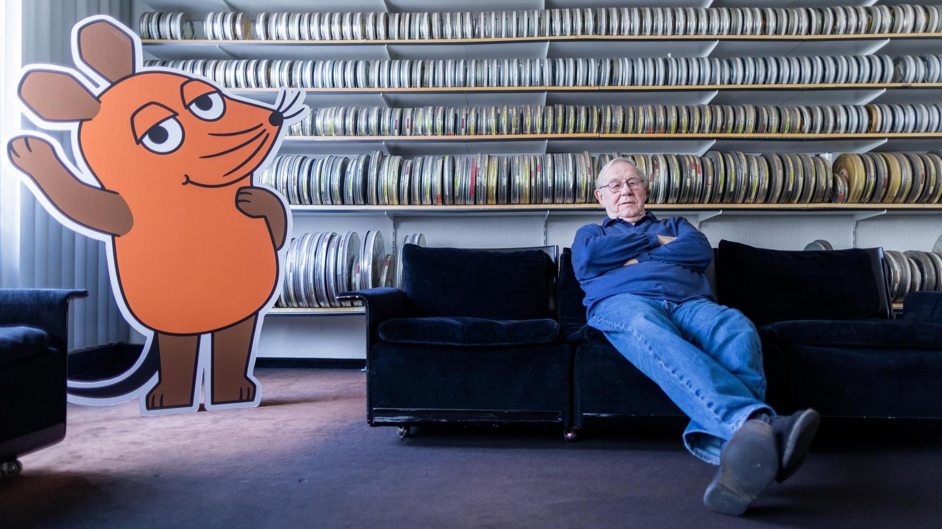 Armin Maiwald, Filmemacher, Autor und Miterfinder der "Sendung mit der Maus" sitzt auf einem Sofa in seinem Büro vor zahlreichen Filmrollen.