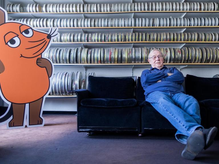 Armin Maiwald, Filmemacher, Autor und Miterfinder der "Sendung mit der Maus" sitzt auf einem Sofa in seinem Büro vor zahlreichen Filmrollen.