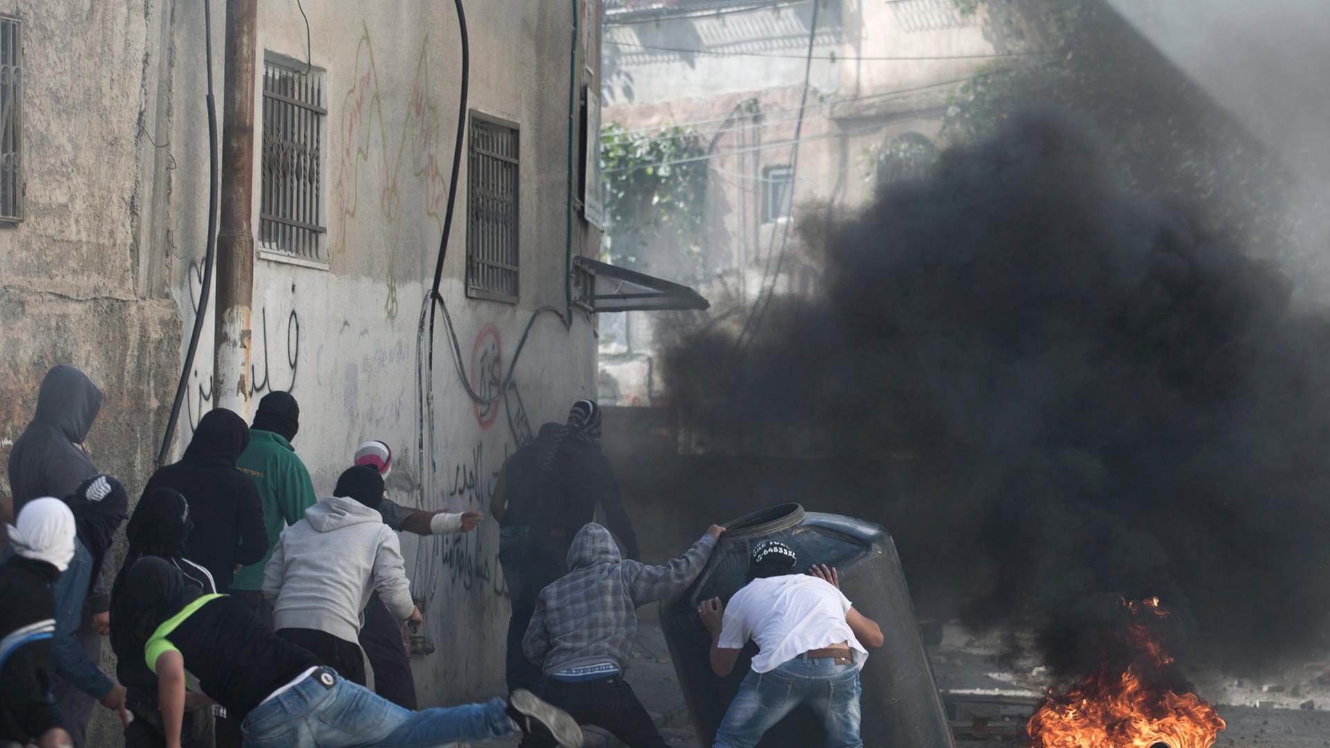 Palästinensische Demonstranten werfen im Osten Jerusalems Steine auf die israelische Polizei (30.10.2014).