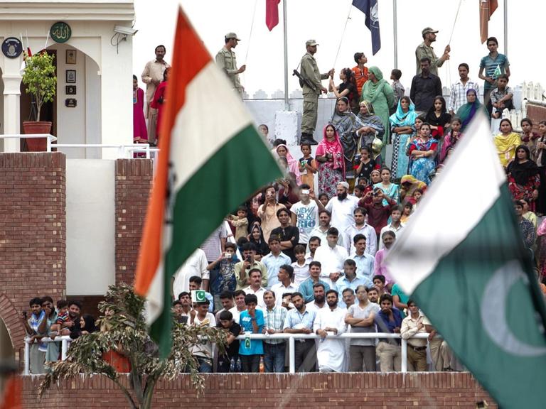 Feierlichkeiten an der Indisch-Pakistanischen Grenze in Wagah - einem Grenzübergang an der Straße zwischen Amritsar, Punjab (Indien) und Lahore, Punjab (Pakistan) sowie Teil der Grand Trunk Road. Es ist der einzige Grenzübergang in den genannten Bundesstaaten zwischen Indien und Pakistan. Im Vordergrund sind die Flaggen Indiens und Pakistans zu sehen.