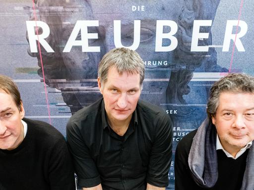 Reimer Bustorff (l-r) und Marcus Wiebusch, Musiker der Band Kettcar sowie Daniel Karasek, Generalintendant des Schauspiels Kiel, vor dem Plakat zur Inszenierung "Die Räuber"