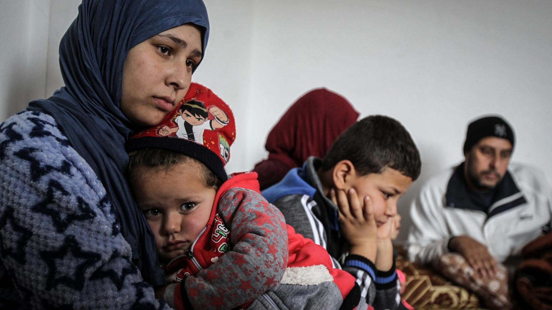Die 19-jährige Syrerin Amal (l) umarmt ihre dreijährige Tochter Grufran neben ihrem Bruder Mohommad (M) und ihrem Vater Shihab Ahmad al-Abed (r) in einer Wohnung. Amal, ihre Tochter, ihr Vater und ihr Bruder überlebten die illegale Grenzüberquerung von Syrien in den Libanon, bei der mehrere andere Syrer erfroren. Der Libanon beheimatet derzeit mehr als eine Million vor dem Bürgerkrieg geflohene Syrer.