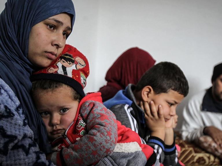 Die 19-jährige Syrerin Amal (l) umarmt ihre dreijährige Tochter Grufran neben ihrem Bruder Mohommad (M) und ihrem Vater Shihab Ahmad al-Abed (r) in einer Wohnung. Amal, ihre Tochter, ihr Vater und ihr Bruder überlebten die illegale Grenzüberquerung von Syrien in den Libanon, bei der mehrere andere Syrer erfroren. Der Libanon beheimatet derzeit mehr als eine Million vor dem Bürgerkrieg geflohene Syrer.