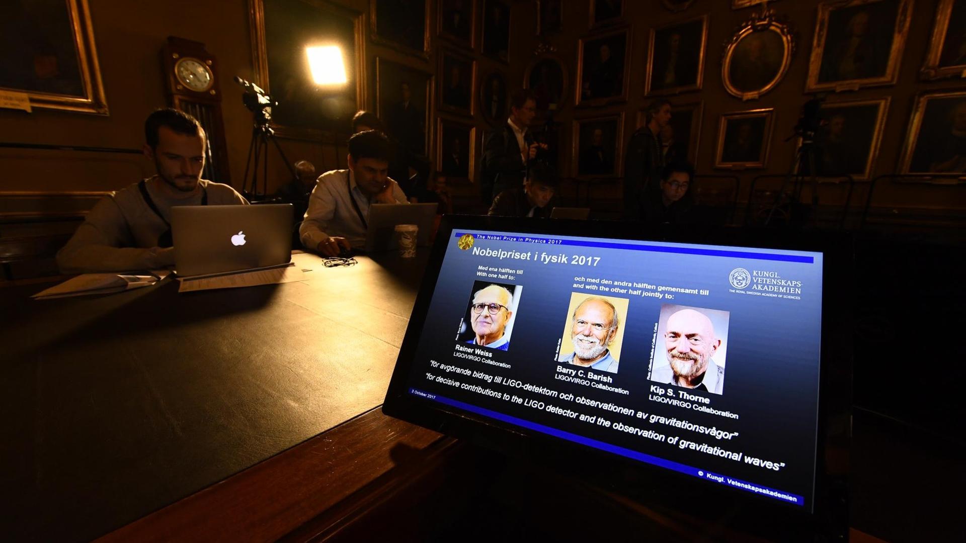 von links nach rechts: Rainer Weiss, Barry C Barish und Kip S Thorne sieht man auf dem Bildschirm eines Computers bei der Verkündung des Nobelpreises für Physik 2017 von links nach rechts: Rainer Weiss, Barry C Barish und Kip S Thorne sieht man auf dem Bildschirm eines Computers bei der Verkündung des Nobelpreises für Physik 2017