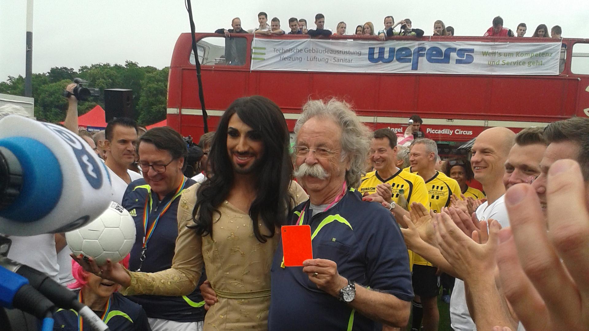 Ein Conchita-Wurst-Double und Jean Pütz, der eine rote Karte in der Hand hält. Ein Conchita-Wurst-Double und Jean Pütz, der eine rote Karte in der Hand hält.