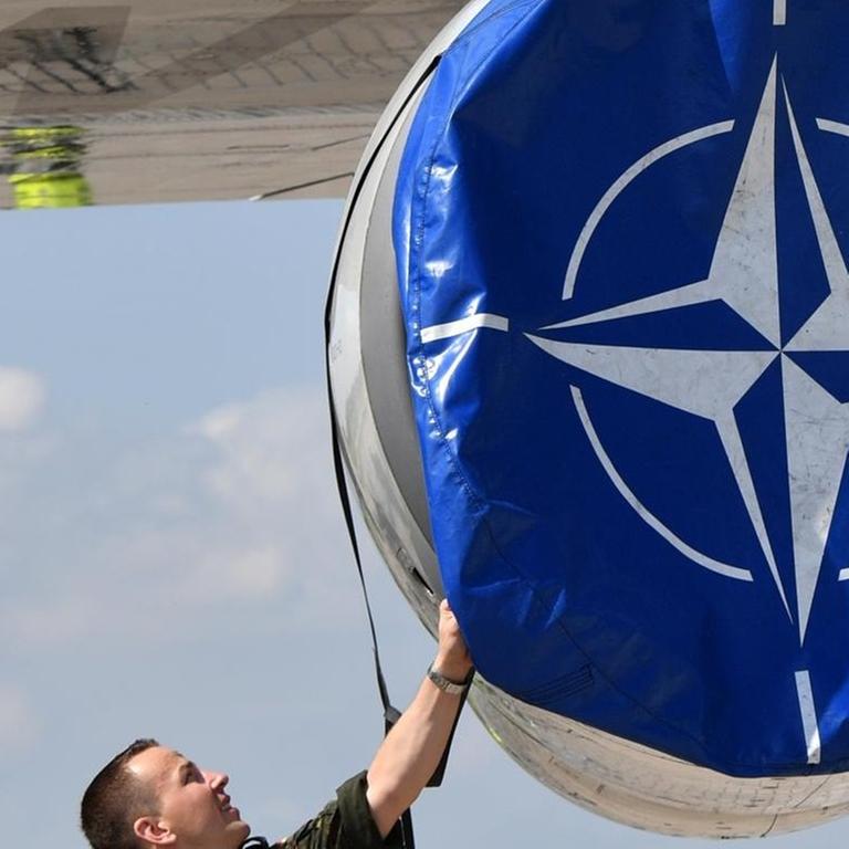 Mechaniker hanitieren in Schönefeld (Brandenburg) auf der Internationalen Luft- und Raumfahrtmesse ILA an einer Schutzhülle mit dem Logo der Nato an einem AWACS Aufklärungsflugzeug
