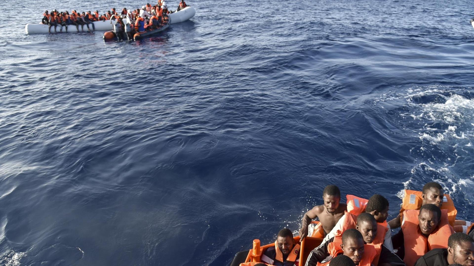 Mitglieder der Maltesischen NGO-Organisation MOAS helfen am 3.11.2016 Flüchtlingen an Bord eines kleinen Rettungsbootes während einer gemeinsamen Rettungsaktion mit dem Italienischen Roten Kreuz vor der Küste Libyens. Mitglieder der Maltesischen NGO-Organisation MOAS helfen am 3.11.2016 Flüchtlingen an Bord eines kleinen Rettungsbootes während einer gemeinsamen Rettungsaktion mit dem Italienischen Roten Kreuz vor der Küste Libyens.