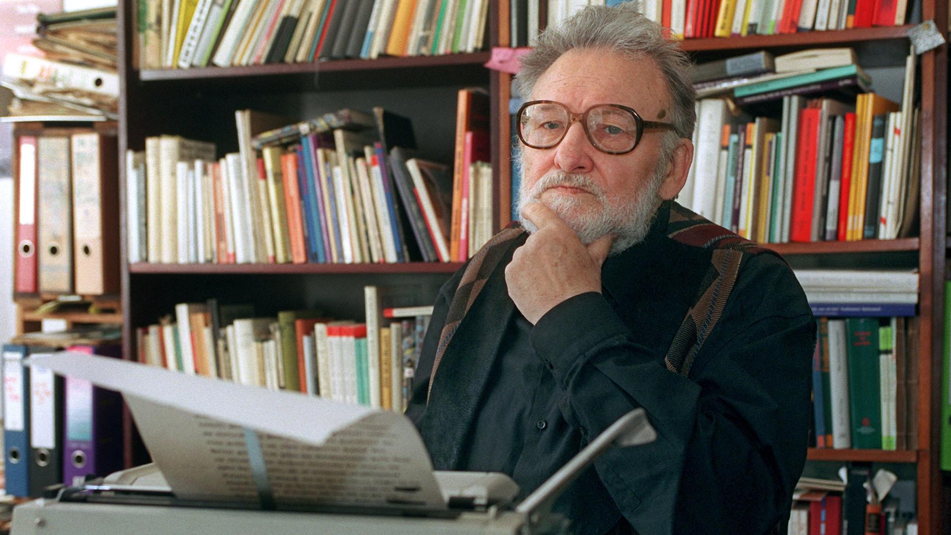 Der Schriftsteller Adolf Endler sitzt vor einer Schreibmaschine, hinter ihm ein volles Bücherregal. Der Schriftsteller Adolf Endler sitzt vor einer Schreibmaschine, hinter ihm ein volles Bücherregal.