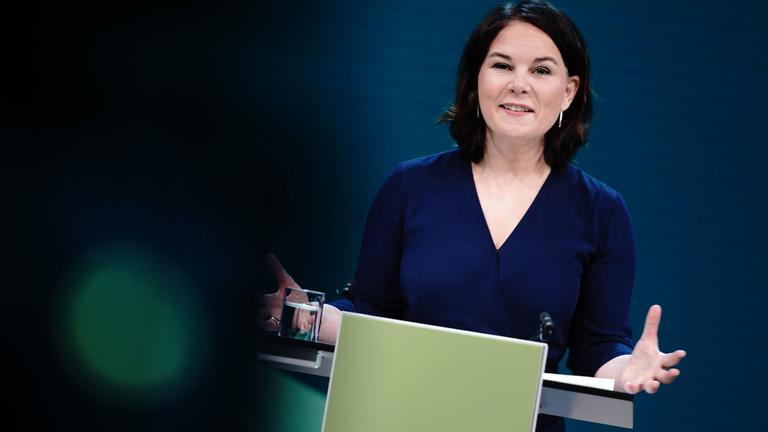 Die Grünen-Vorsitzende Annalena Baerbock steht hinter einem Mikrofon.