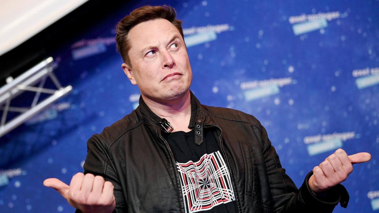 Elon Musk schaut mit hoch erhobene Augenbrauen zur Seite und gestikuliert mit seinen Händen. Elon Musk schaut mit hoch erhobene Augenbrauen zur Seite und gestikuliert mit seinen Händen.