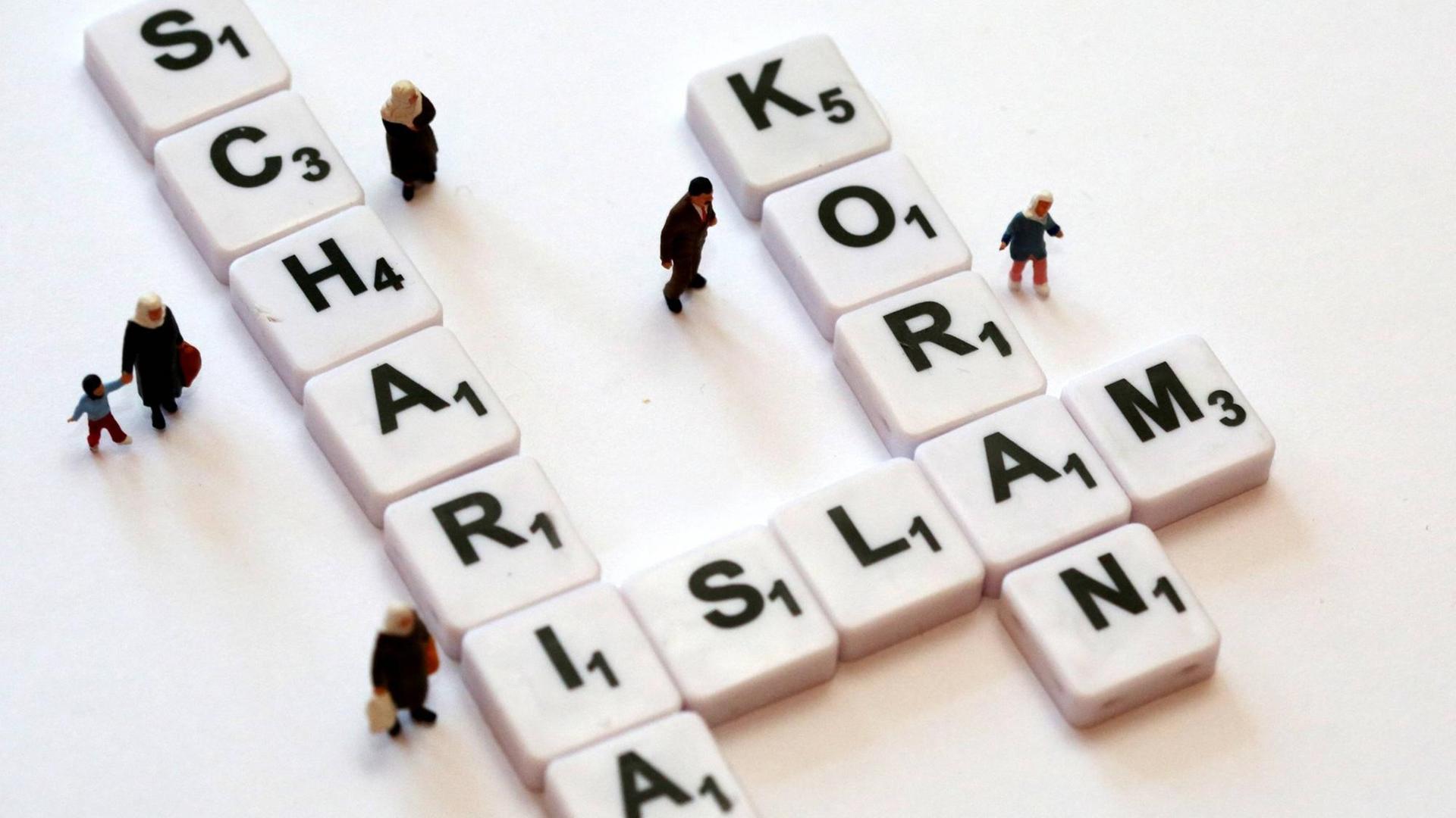 Mit Buchstabenplättchen sind die Worte "Scharia", "Islam" und "Koran" gelegt. Kleine Menschen-Figuren stehen um die Buchstaben herum Mit Buchstabenplättchen sind die Worte "Scharia", "Islam" und "Koran" gelegt. Kleine Menschen-Figuren stehen um die Buchstaben herum
