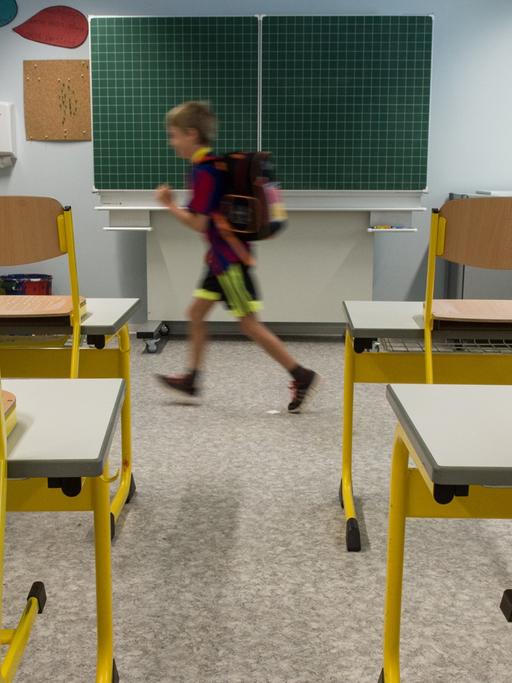 Eine Grundschüler läuft durch ein leeres Klassenzimmmer.