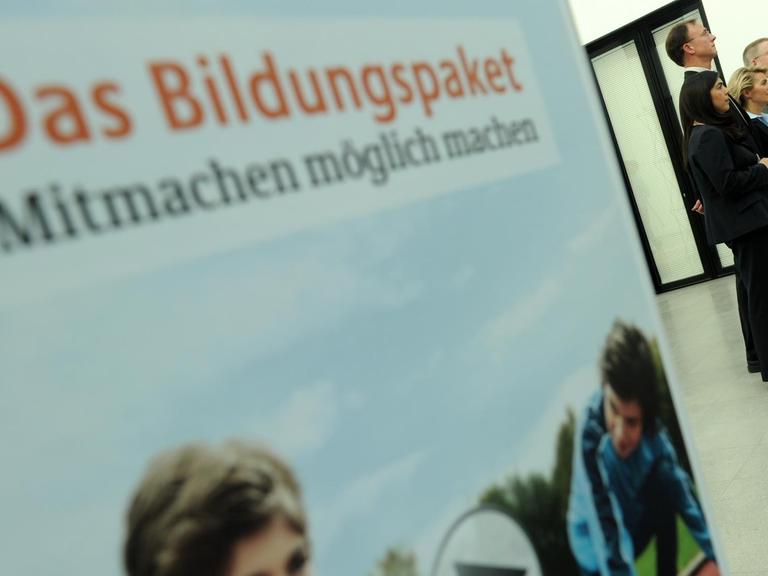 Auf einem Plakat steht "Das Bildungspaket - Mitmachen möglich machen", im Hintergrund stehen Politiker, unter ihnen Ursula von der Leyen, an Mikrofonen und sprechen.
