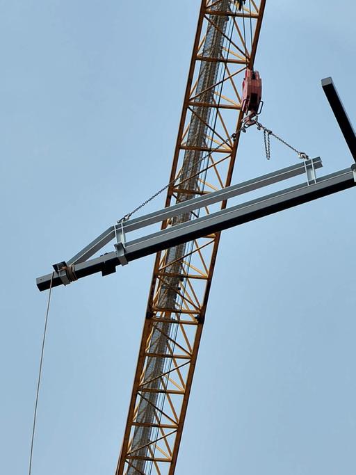 Ein christliches Kreuz hängt an einem Kran.