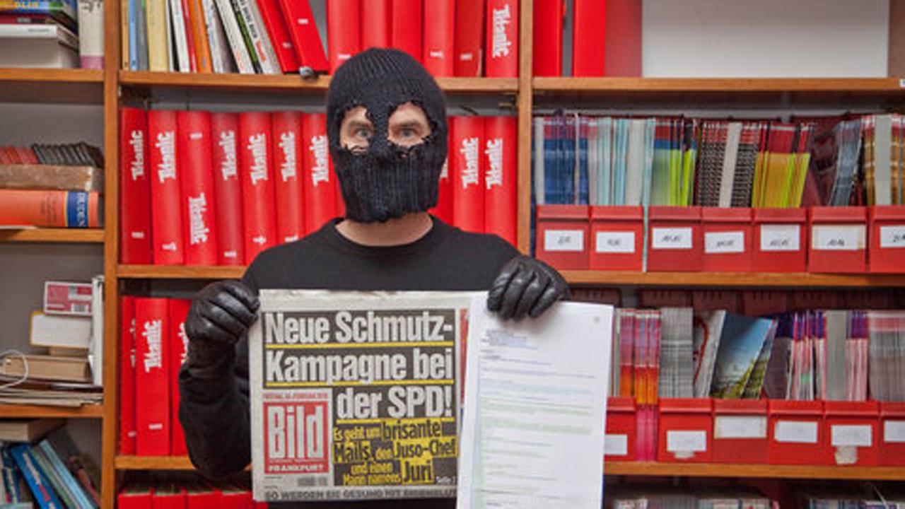 Das Bild eines Maskierten, der eine "Bild"-Zeitung in der Hand hält. Das Bild eines Maskierten, der eine "Bild"-Zeitung in der Hand hält.