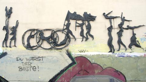 Auf dem Giebel einer ehemaligen Sporteinrichtung der DDR ist ein Relief dargestellt, darunter ein Graffiti "Du warst der Beste". In Höhenschönhausen.