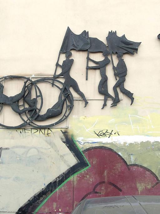 Auf dem Giebel einer ehemaligen Sporteinrichtung der DDR ist ein Relief dargestellt, darunter ein Graffiti "Du warst der Beste". In Höhenschönhausen.