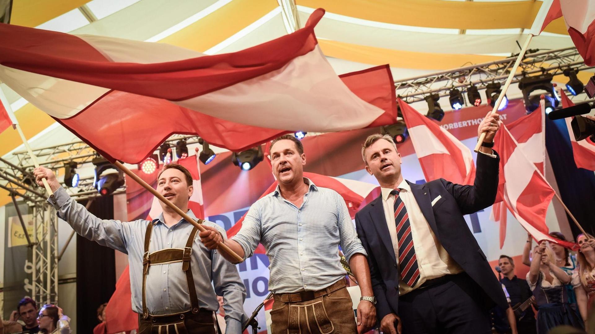 FPÖ-Kandidat Hofer (r.), Parteichef Strache (M.) und der Landeshauptmann-Stellvertreter Oberösterreichs, Haimbuchner (l.), schenken auf der FPÖ-Auftaktveranstaltung zum Wahkampf der wiederholten Präsidentenwahl Fahnen. FPÖ-Kandidat Hofer (r.), Parteichef Strache (M.) und der Landeshauptmann-Stellvertreter Oberösterreichs, Haimbuchner (l.), schenken auf der FPÖ-Auftaktveranstaltung zum Wahkampf der wiederholten Präsidentenwahl Fahnen.