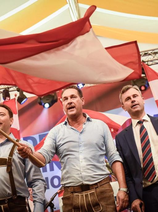 FPÖ-Kandidat Hofer (r.), Parteichef Strache (M.) und der Landeshauptmann-Stellvertreter Oberösterreichs, Haimbuchner (l.), schenken auf der FPÖ-Auftaktveranstaltung zum Wahkampf der wiederholten Präsidentenwahl Fahnen.