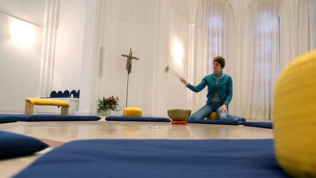 Die Pastorin der Kirche der Stille, Irmgard Nauck, schlägt in Hamburg im Innenraum der Kirche gegen eine Klangschale.