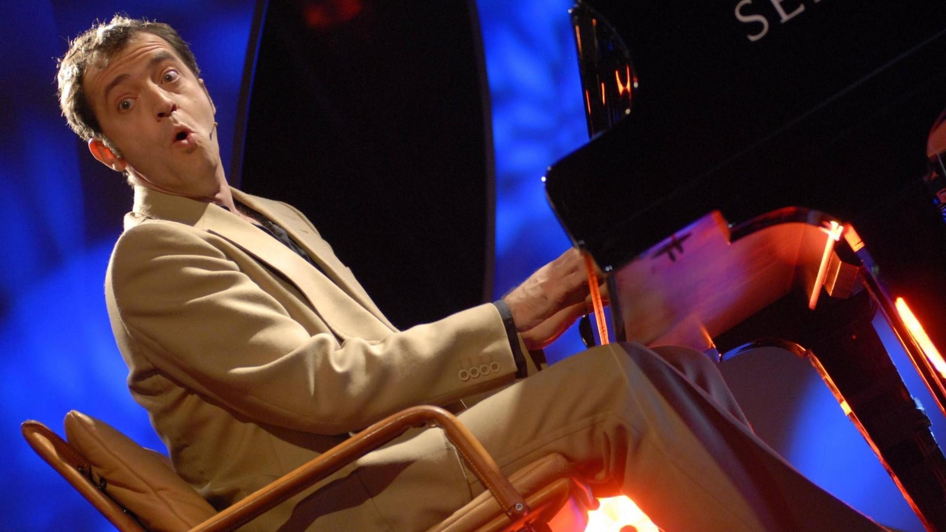 Der Liedermacher Rainald Grebe auf der Bühne am Klavier bei einem Konzert. Der Liedermacher Rainald Grebe auf der Bühne am Klavier bei einem Konzert.