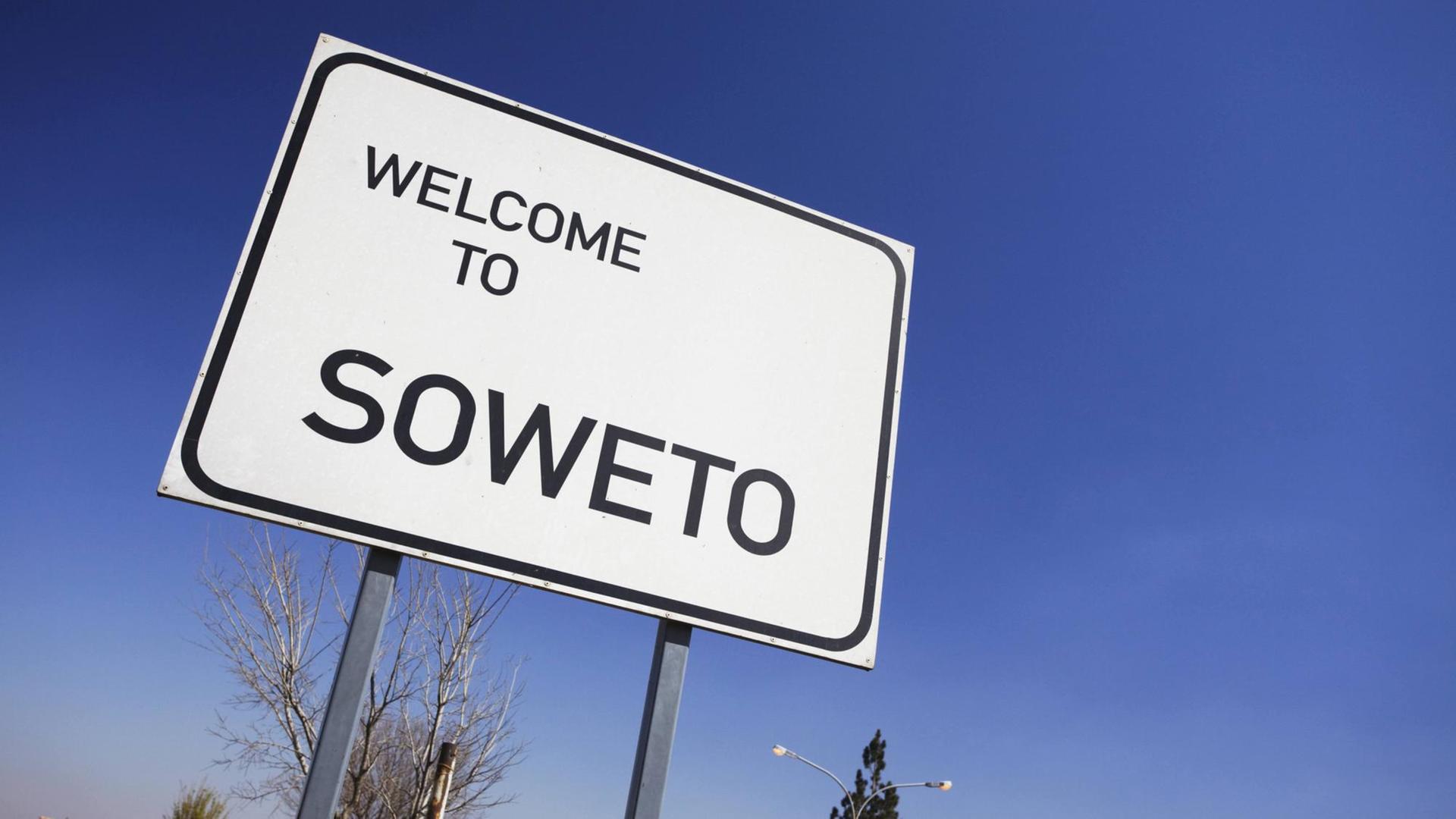 Straßenschild vor blauem Himmel, auf dem "Welcome to Soweto" – Herzlich Willkommen in Soweto – steht Straßenschild vor blauem Himmel, auf dem "Welcome to Soweto" – Herzlich Willkommen in Soweto – steht