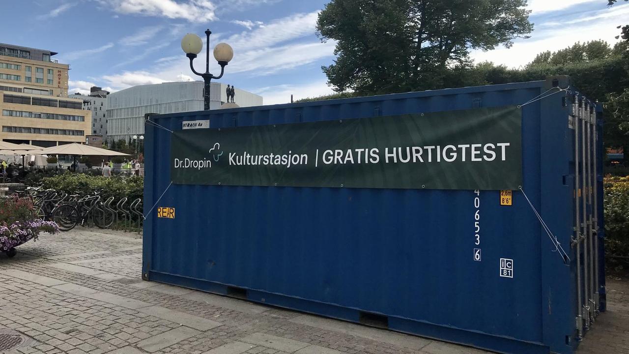 Ein großer blauer Container steht auf einem leeren Platz. Darauf steht: "Kostenloser Schnelltest". Ein großer blauer Container steht auf einem leeren Platz. Darauf steht: "Kostenloser Schnelltest".