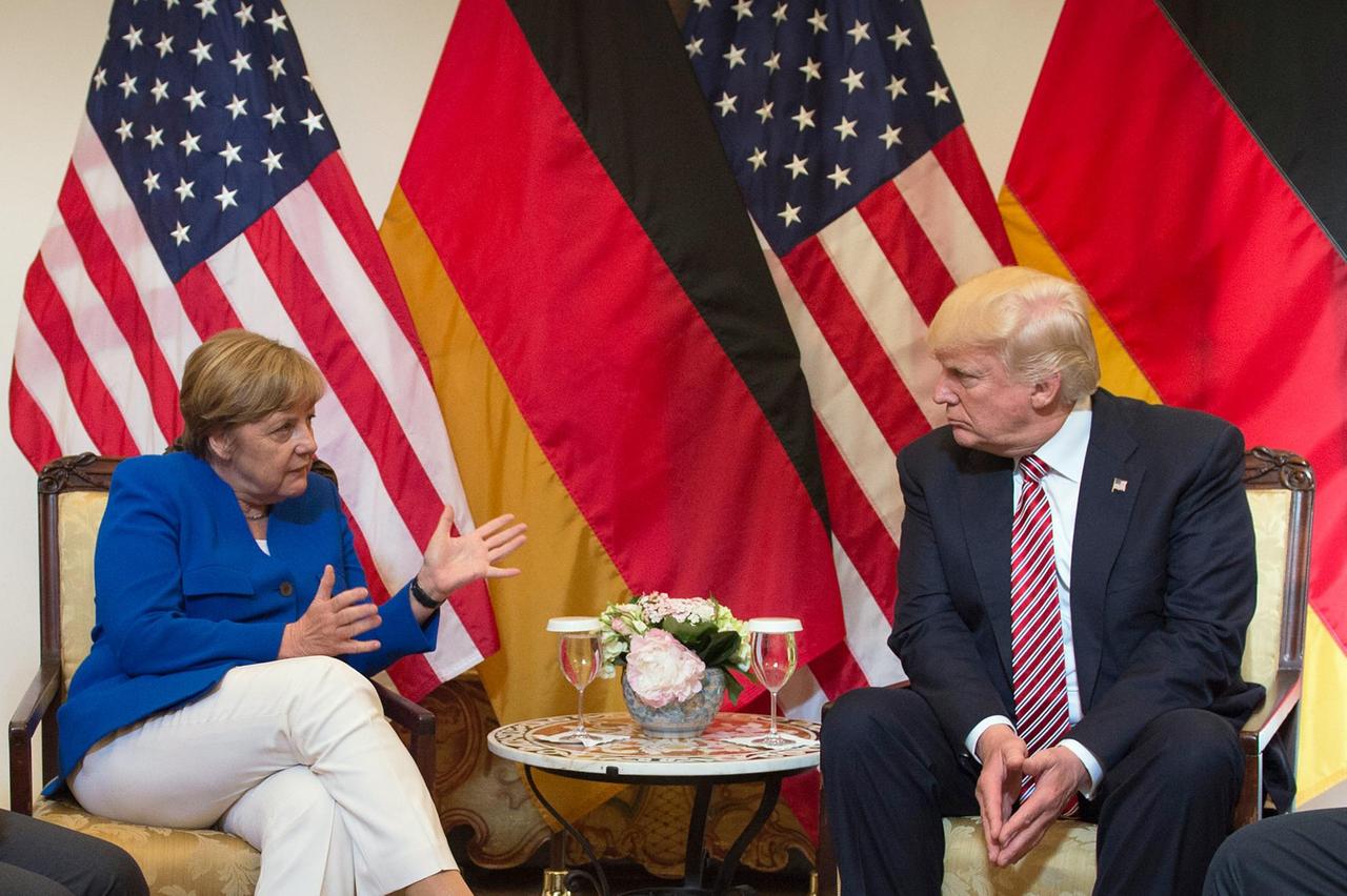 Das Bild zeigt Bundeskanzlerin Angela Merkel und US-Präsident Donald Trump. Sei sprechen am 26.05.2017 während des G7-Gipfeltreffens in Taormina auf Sizilien (Italien). Sie sitzen vor deutschen und amerikanischen Flaggen an einem Tisch und schauen sich ernt an. Das Bild zeigt Bundeskanzlerin Angela Merkel und US-Präsident Donald Trump. Sei sprechen am 26.05.2017 während des G7-Gipfeltreffens in Taormina auf Sizilien (Italien). Sie sitzen vor deutschen und amerikanischen Flaggen an einem Tisch und schauen sich ernt an.