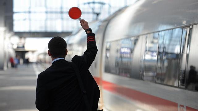 Ein Zugbegleiter gibt am Hauptbahnhof in München das Signal zur Abfahrt.