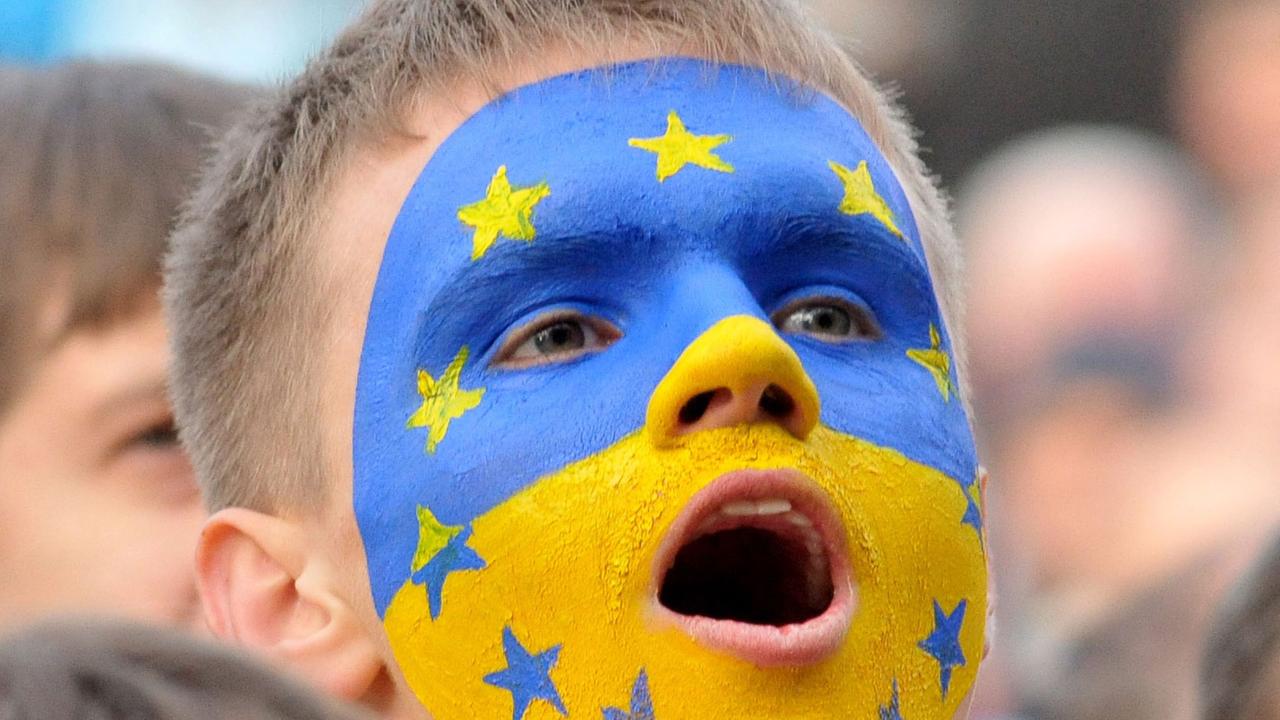 Ein Junge mit einer ins Gesicht gemalten gelb-blauen ukrainischen Flagge, auf der auch die Sterne der EU-Fahne zu sehen sind. Ein Junge mit einer ins Gesicht gemalten gelb-blauen ukrainischen Flagge, auf der auch die Sterne der EU-Fahne zu sehen sind.