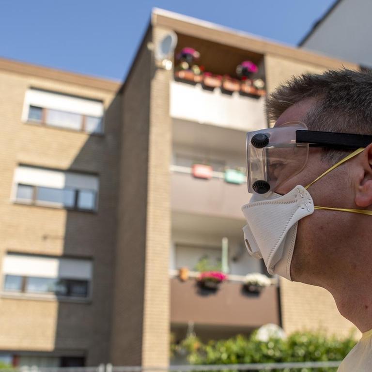 Ein Helfer vom Roten Kreuz steht mit FFP-Maske vor einem abgesperrten Wohnhaus. Die Stadt Verl hat nach positiven Corona-Tests bei zahlreichen Tönnies-Mitarbeitern im Stadtteil Sürenheide eine Quarantäne eingerichtet. 