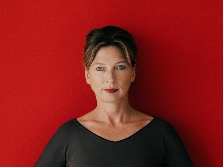 Porträt von Iris Laufenberg vor roter Wand.
