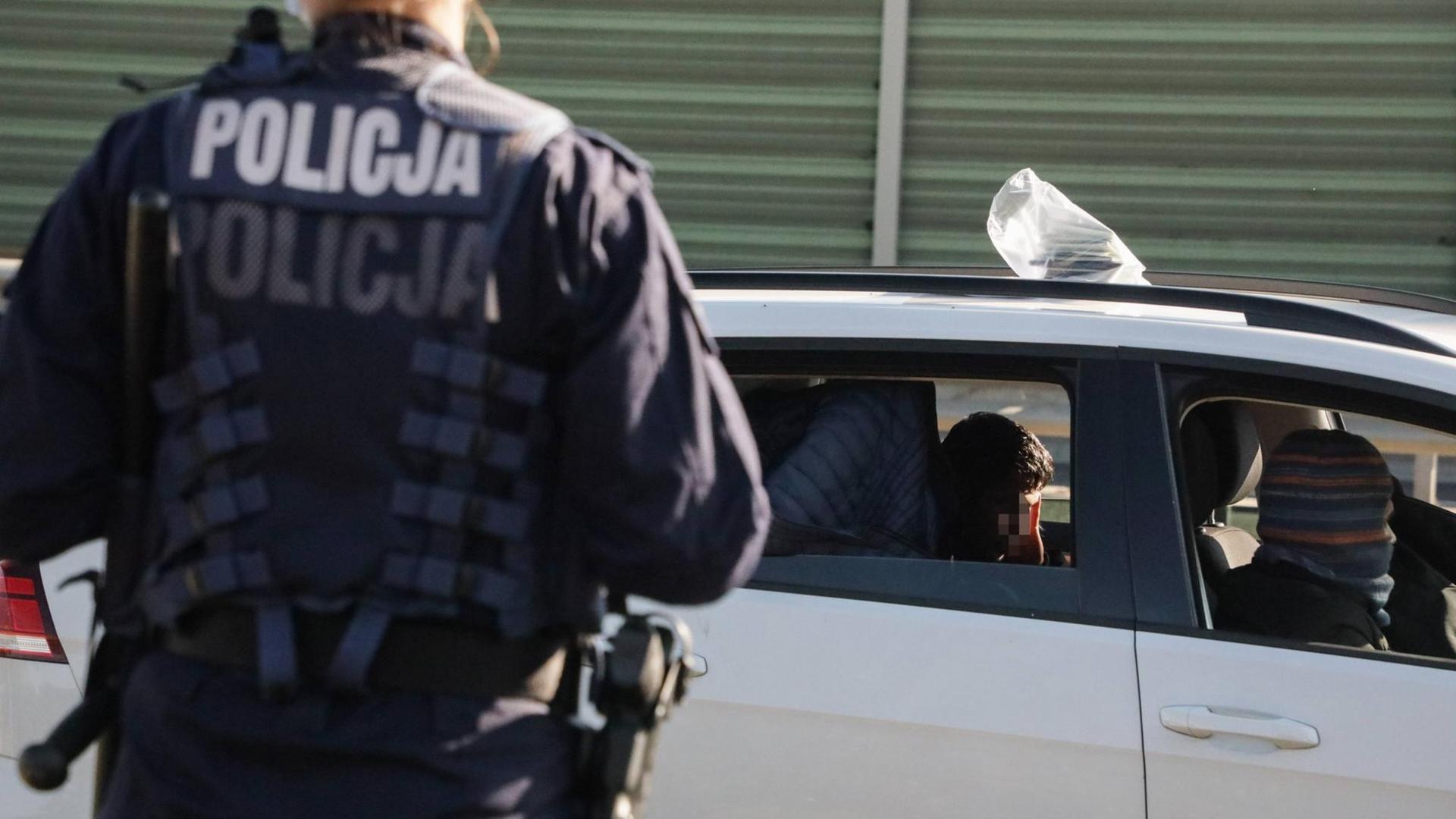 Ein Polizist steht am 3.10.2021 an der polnisch-belarussischen Grenze und kontrolliert PKW Ein Polizist steht am 3.10.2021 an der polnisch-belarussischen Grenze und kontrolliert PKW