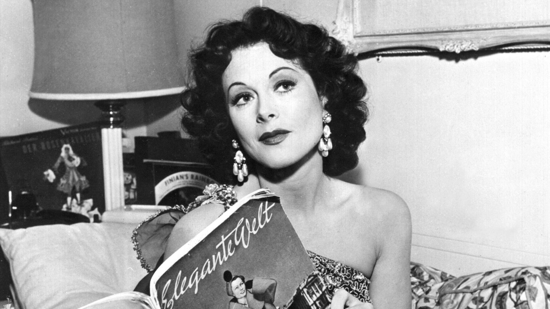 Die amerikanische Schauspielerin Hedy Lamarr blättert in der "Eleganten Welt" (undatiert). Hedy Lamarr, die in den 30er Jahren als "exotischer Sex-Star" in Hollywood Ruhm erlangte, ist am 19.1.2000 tot in ihrem Haus bei Orlando in Florida aufgefunden worden. Die gebürtige Österreicherin starb im Alter von 86 Jahren. Lamarr bekam aus Hollywood erste Rollenangebote, nachdem sie 1933 für einen Moment fast nackt in dem tschechischen Film "Ekstase" zu sehen gewesen war. Viele Jahre war die Ehefrau eines österreichischen Waffenhändlers danach in den USA auf die Rolle der "schönen Exotin" festgelegt. Sie war aber auch als Erfinderin tätig. 1942 erhielt Lamarr das Patent für eine spezielle Funktechnik. Das Verfahren wurde später bei der Entwicklung von Handys genutzt. Die amerikanische Schauspielerin Hedy Lamarr blättert in der "Eleganten Welt" (undatiert). Hedy Lamarr, die in den 30er Jahren als "exotischer Sex-Star" in Hollywood Ruhm erlangte, ist am 19.1.2000 tot in ihrem Haus bei Orlando in Florida aufgefunden worden. Die gebürtige Österreicherin starb im Alter von 86 Jahren. Lamarr bekam aus Hollywood erste Rollenangebote, nachdem sie 1933 für einen Moment fast nackt in dem tschechischen Film "Ekstase" zu sehen gewesen war. Viele Jahre war die Ehefrau eines österreichischen Waffenhändlers danach in den USA auf die Rolle der "schönen Exotin" festgelegt. Sie war aber auch als Erfinderin tätig. 1942 erhielt Lamarr das Patent für eine spezielle Funktechnik. Das Verfahren wurde später bei der Entwicklung von Handys genutzt.