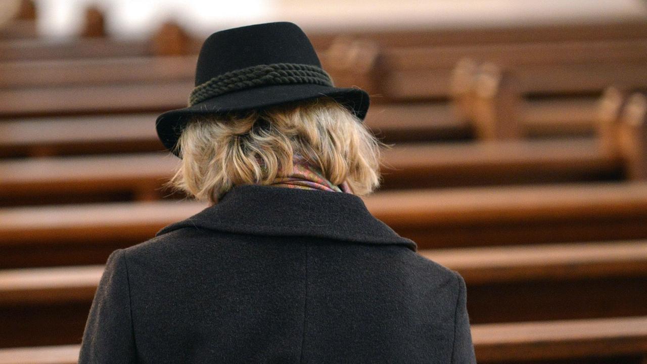 Einzelne Frau auf sonst leeren Kirchenbänken - von Generation zu Generation verliert die Kirche an Bedeutung. Einzelne Frau auf sonst leeren Kirchenbänken - von Generation zu Generation verliert die Kirche an Bedeutung.