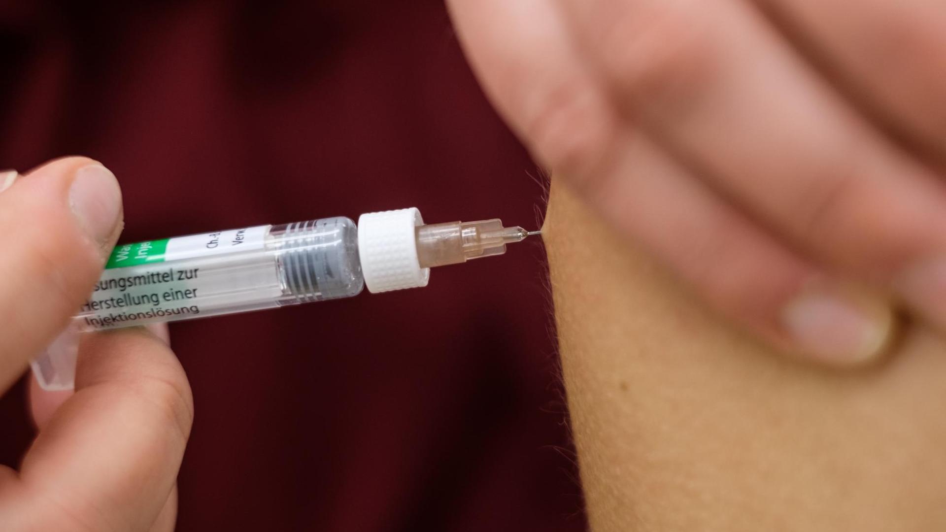 Eine Arzthelferin impft in einer Arztpraxis eine Patientin mit einer Spritze. Eine Arzthelferin impft in einer Arztpraxis eine Patientin mit einer Spritze.