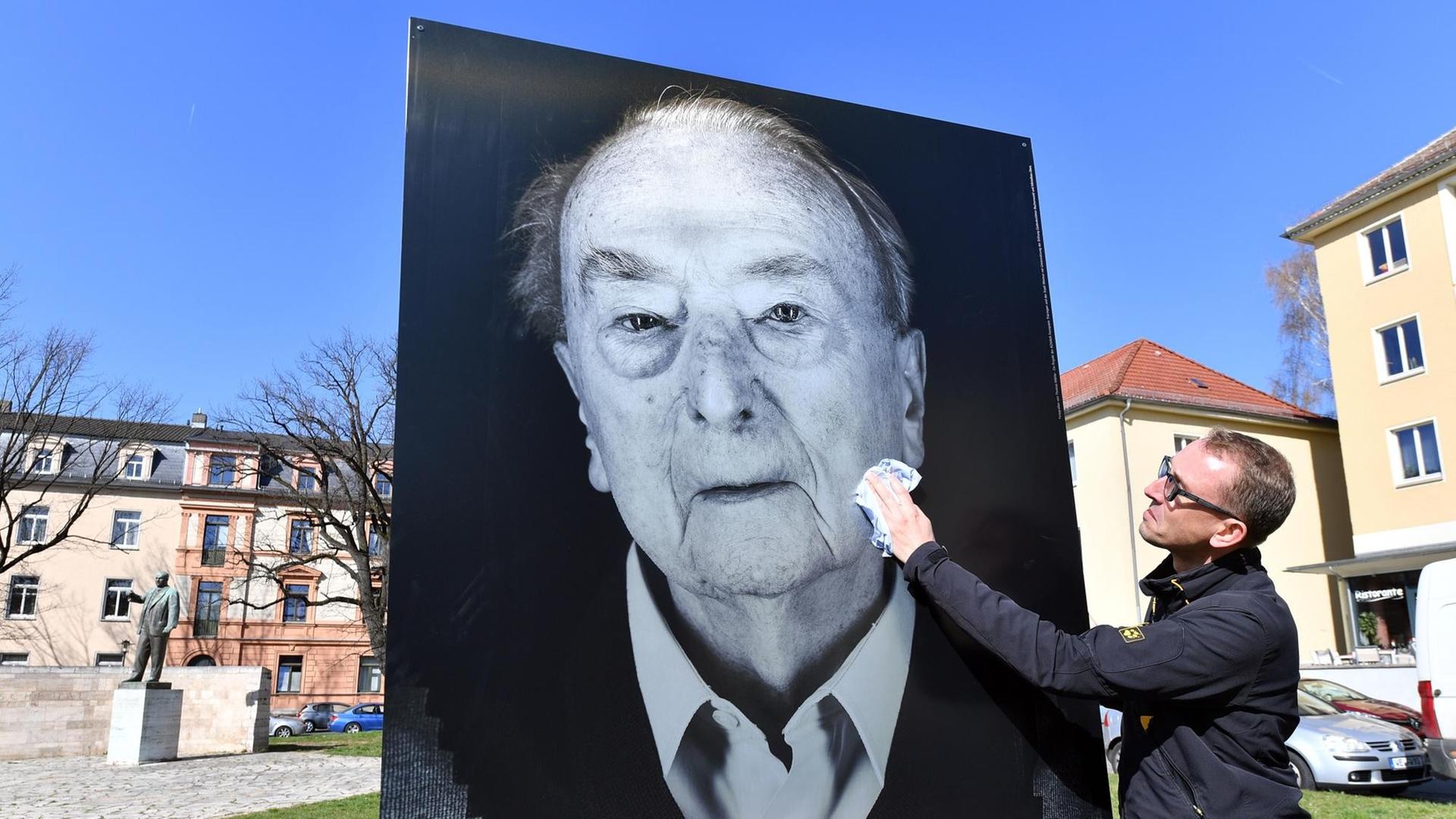 Der Fotograf Thomas Müller wischt vor der Eröffnung der Open-Air-Ausstellung "Die Zeugen" über eines seiner Bilder. Seine Porträts von Überlebenden des Konzentrationslagers Buchenwald als überlebensgroße Bilder säumen die Straße von Weimarer Hauptbahnhof bis zum neuen Bauhaus-Museum. Der Fotograf Thomas Müller wischt vor der Eröffnung der Open-Air-Ausstellung "Die Zeugen" über eines seiner Bilder. Seine Porträts von Überlebenden des Konzentrationslagers Buchenwald als überlebensgroße Bilder säumen die Straße von Weimarer Hauptbahnhof bis zum neuen Bauhaus-Museum.