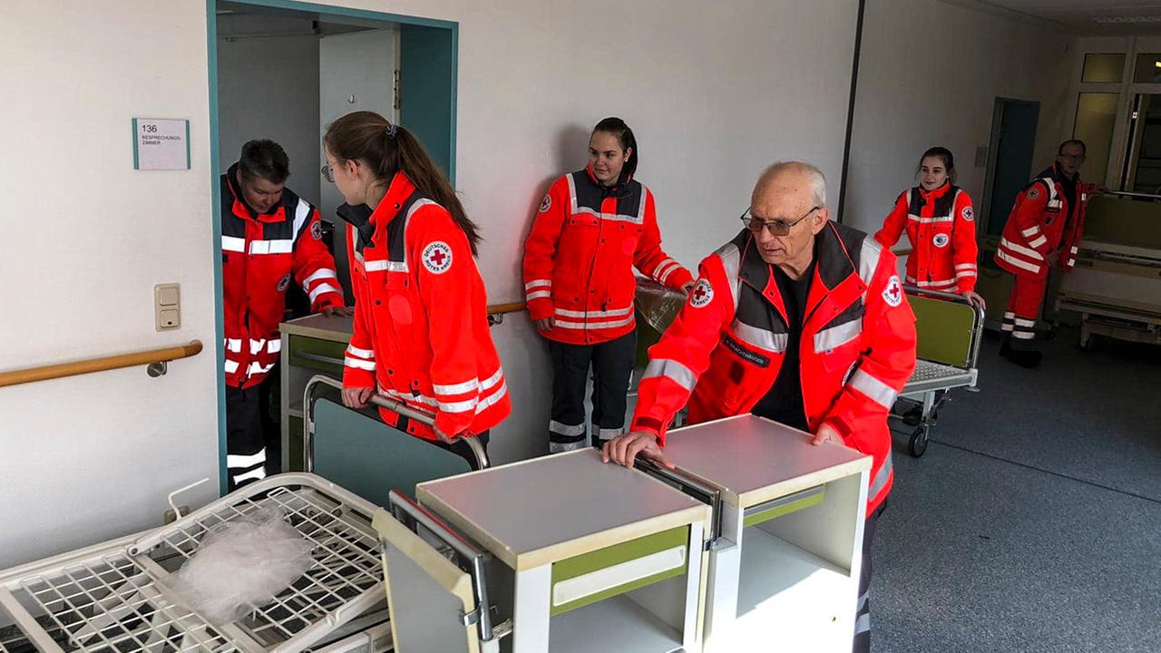 Mitarbeiter des Deutschen Roten Kreuzes bringen Rollschränke und andere neue Ausrüstungsgegenstände für das Krankenhaus in Kredenbach, das wegen der Coronapandemie 2020 reaktiviert wird.