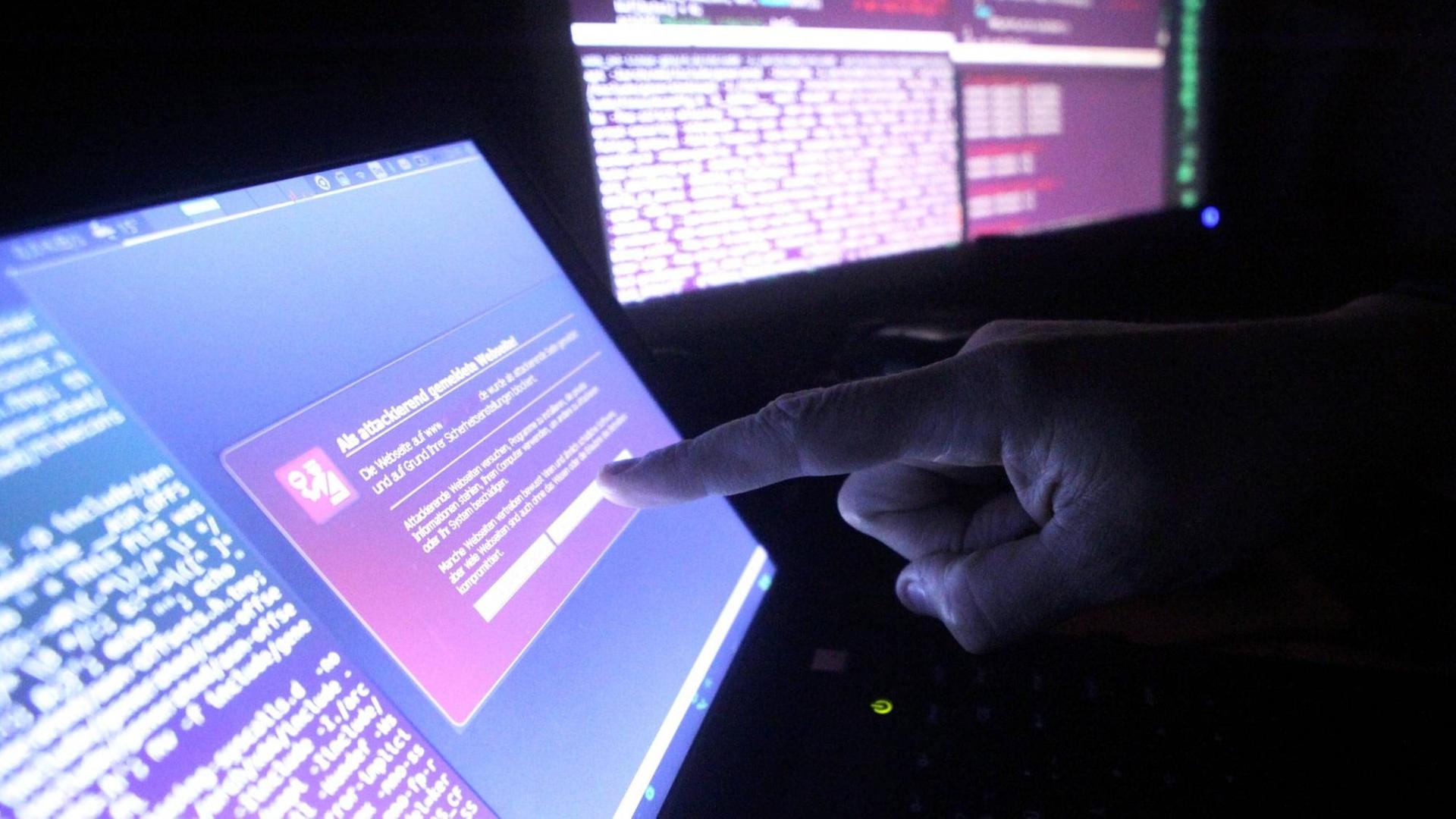 Symbolfoto zum Thema Internetkriminalität: eine Hand vor einem Computer-Monitor