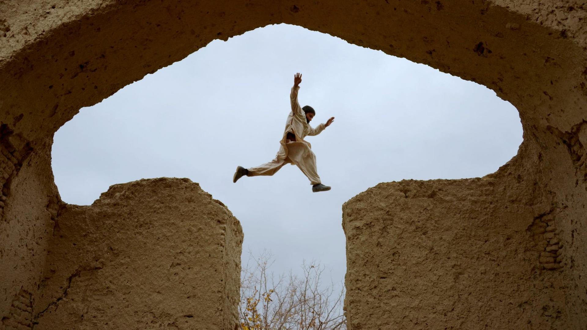 Ein afghanischer Junge springt in den Ruinen des Hauses, in dem der persische Poet Rumi im 13.Jahrhundert gelebt hat, Mazar-i-Sharif, Afghanistan. Ein afghanischer Junge springt in den Ruinen des Hauses, in dem der persische Poet Rumi im 13.Jahrhundert gelebt hat, Mazar-i-Sharif, Afghanistan.