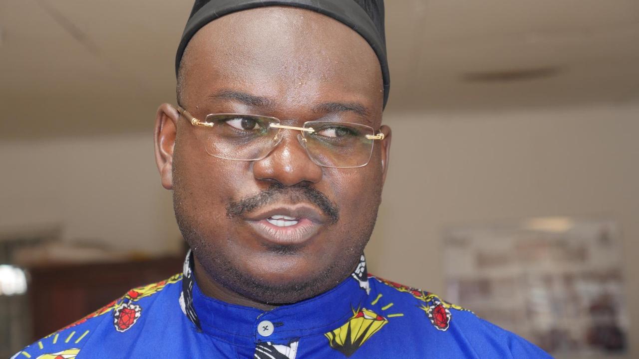 Ngong Betrand Collins von der Stiftung "Africavenir" in Douala findet es wichtig, dass die Kameruner in ihren Muttersprachen von der deutschen Kolonialzeit erfahren. Er trägt ein buntes Gewand und eine schwarze Kopfbedeckung. Ngong Betrand Collins von der Stiftung "Africavenir" in Douala findet es wichtig, dass die Kameruner in ihren Muttersprachen von der deutschen Kolonialzeit erfahren. Er trägt ein buntes Gewand und eine schwarze Kopfbedeckung.