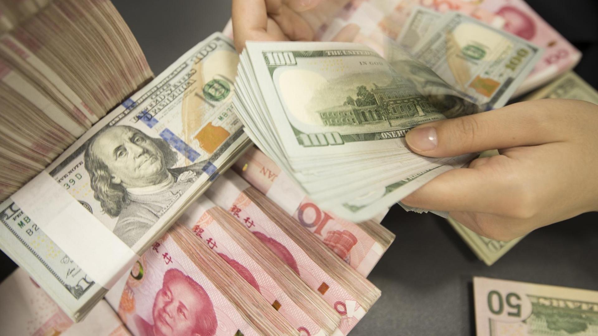06.08.2019, China, Nantong: A Chinese clerk counts US dollar notes over RMB (renminbi) yuan notes at a bank in Hai'an city, Nantong city, east China's Jiangsu province, 6 August 2019. China did not and will not use exchange rates as a measure to cope with trade disputes, and the United States labeling the country as a "currency manipulator" is inconsistent with the quantitative criteria set by the US Treasury itself, the central bank said on Tuesday (6 August 2019). Foto: Xu Jingbai/Imaginechina/dpa | 06.08.2019, China, Nantong: A Chinese clerk counts US dollar notes over RMB (renminbi) yuan notes at a bank in Hai'an city, Nantong city, east China's Jiangsu province, 6 August 2019. China did not and will not use exchange rates as a measure to cope with trade disputes, and the United States labeling the country as a "currency manipulator" is inconsistent with the quantitative criteria set by the US Treasury itself, the central bank said on Tuesday (6 August 2019). Foto: Xu Jingbai/Imaginechina/dpa |