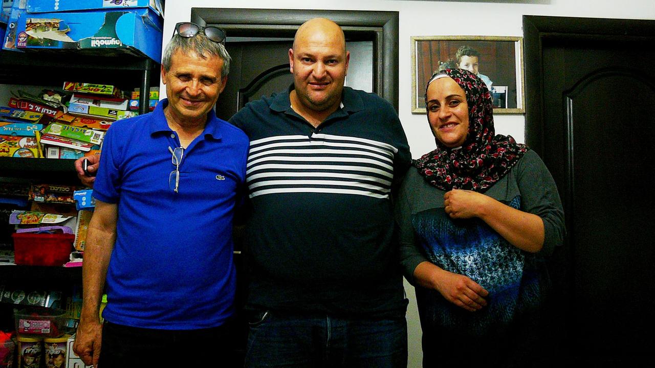Gadi Gvaryahu, Nadja Jaber und ihr Mann stehen nebeneinander in einem Zimmer.