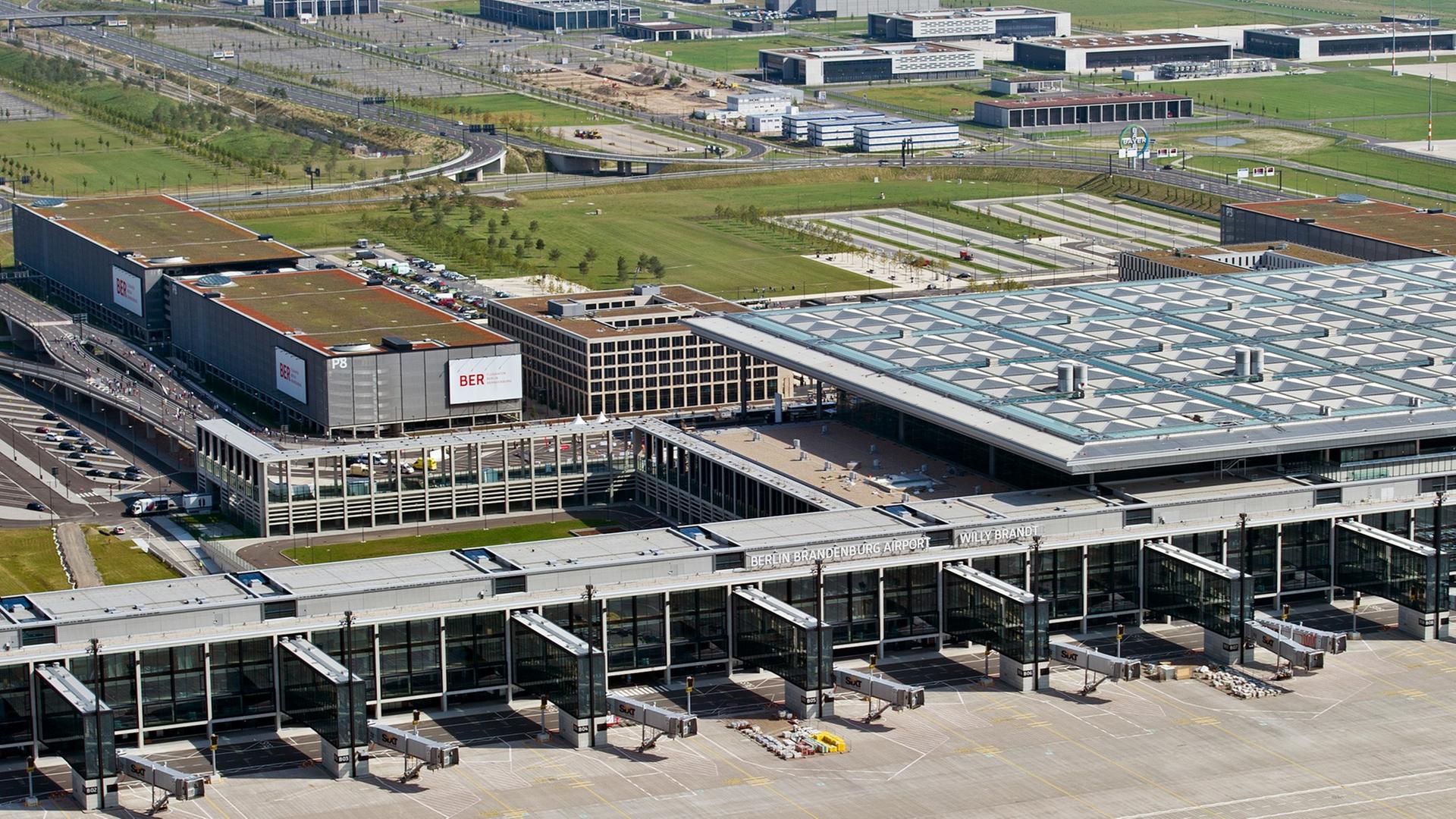 Luftbild eines Terminals des Flughafens mit Vorfeld, Gebäude und Gewerbegebäuden im Hintergrund. Luftbild eines Terminals des Flughafens mit Vorfeld, Gebäude und Gewerbegebäuden im Hintergrund.