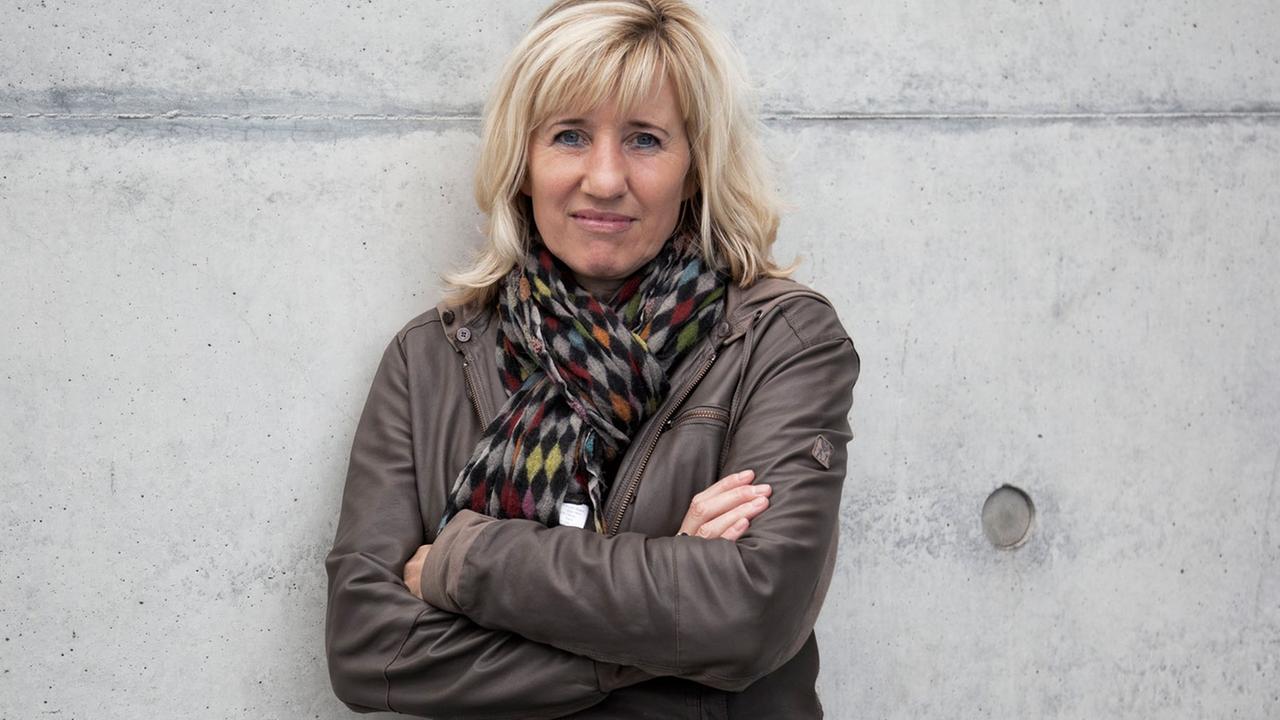 Die Schriftstellerin und Doping-Expertin Ines Geipel, die Arme verschränkt, an eine graue Betonmauer gelehnt. Die Schriftstellerin und Doping-Expertin Ines Geipel, die Arme verschränkt, an eine graue Betonmauer gelehnt.