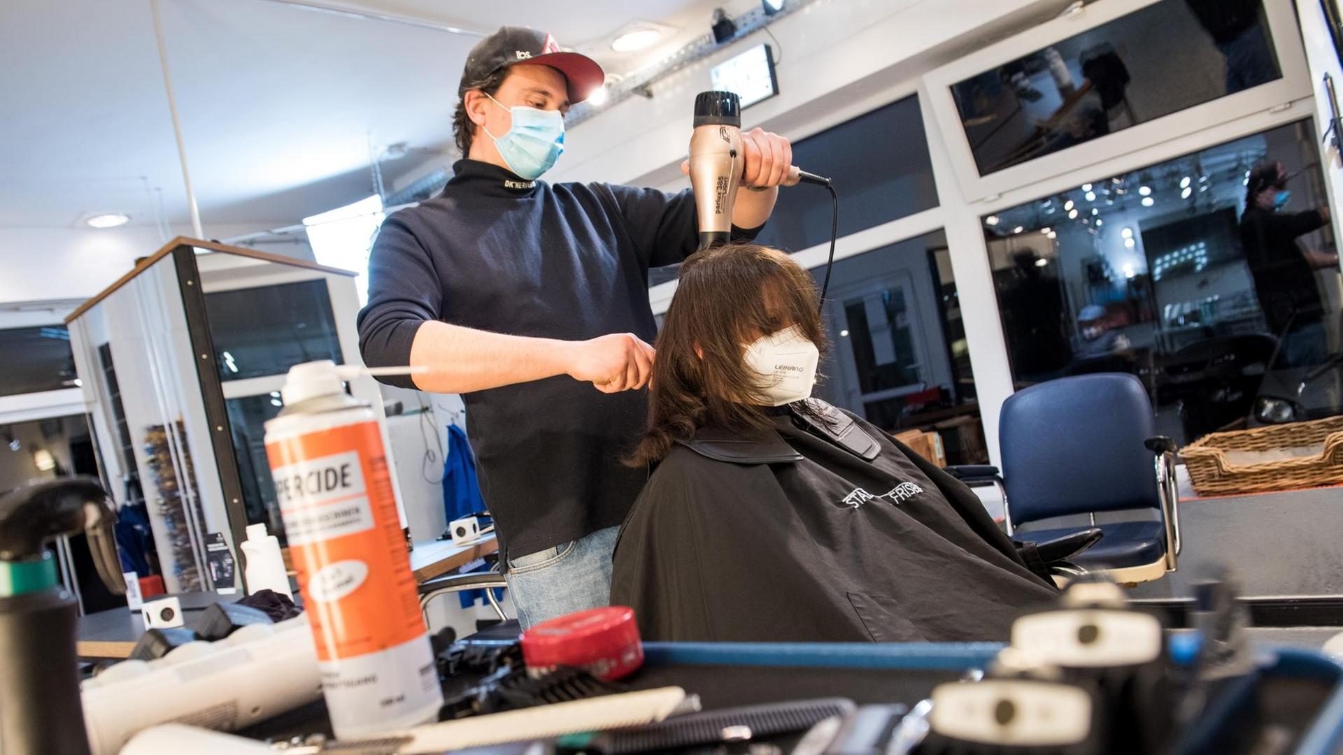 Hamburg: Henry Riehl, Friseur, föhnt Nina Hemkendreis, einer seiner ersten Kunden nach der Wiedereröffnung, kurz nach Mitternacht die Haare. Hamburg: Henry Riehl, Friseur, föhnt Nina Hemkendreis, einer seiner ersten Kunden nach der Wiedereröffnung, kurz nach Mitternacht die Haare.